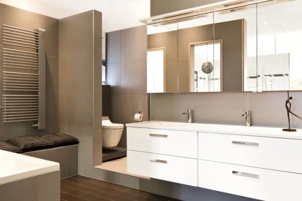 Modernes Bad mit Doppelwaschtisch, Spiegeln, Wand-WC, grauen Fliesen und seitlichem Handtuchheizkörper.